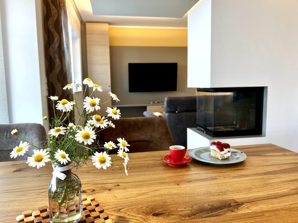Esstisch mit Blumen und Blick auf Fernseher
