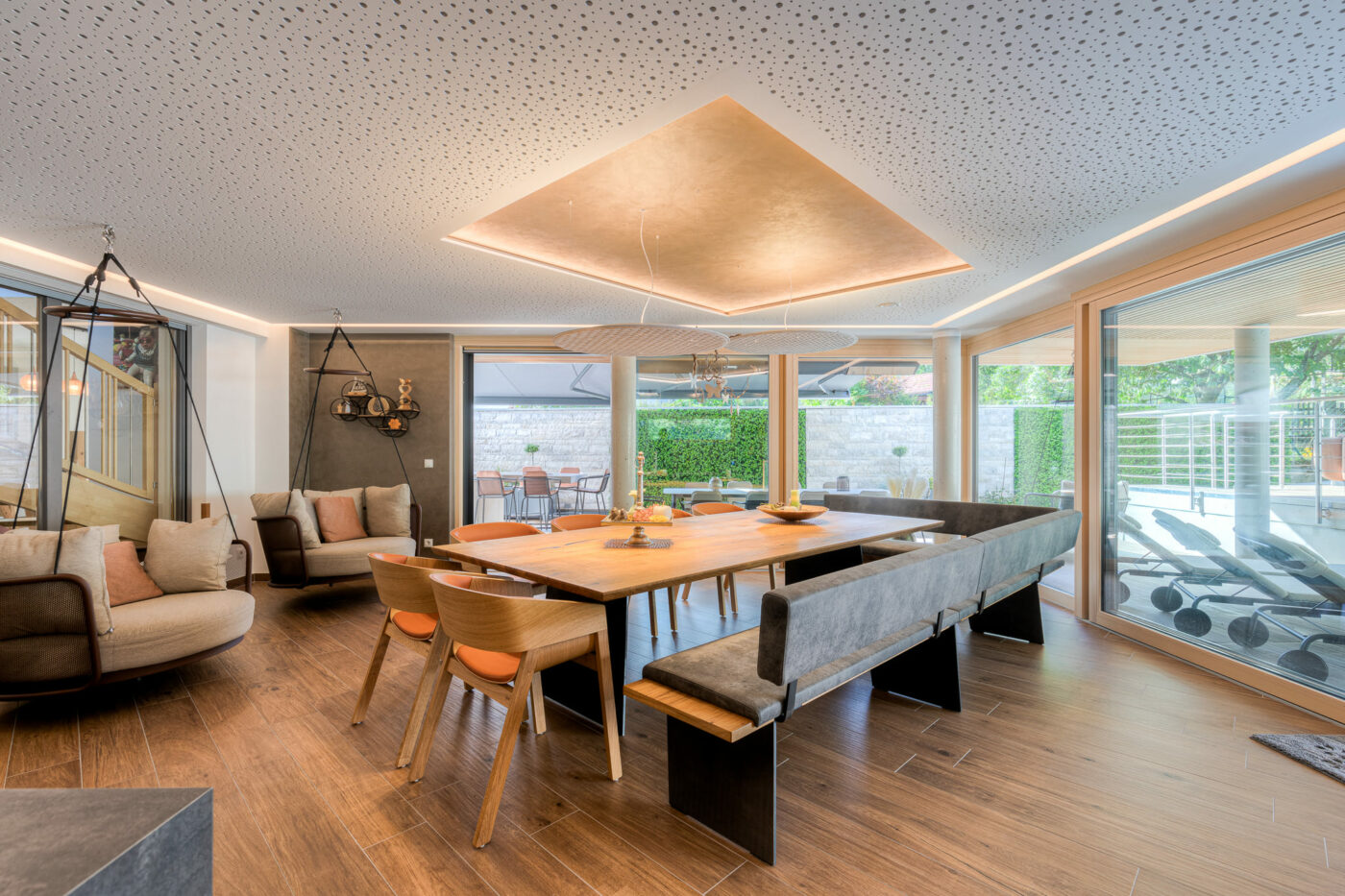 Großer Esstisch mit hochwertigem Licht- & Akustikkonzept. Die Decke erstrahlt in einem goldenen Licht.