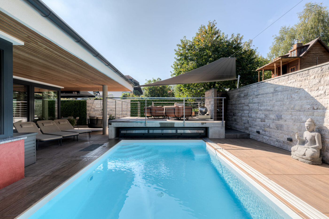 Poollandschaft mit Liege- und Sitzbereich und Sonnensegel