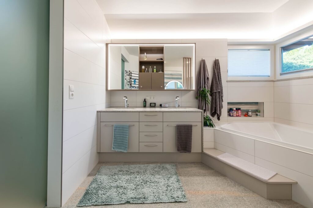 Badezimmer mit Badewanne, beleuchtetem Spiegel und indirekter Deckenbeleuchtung