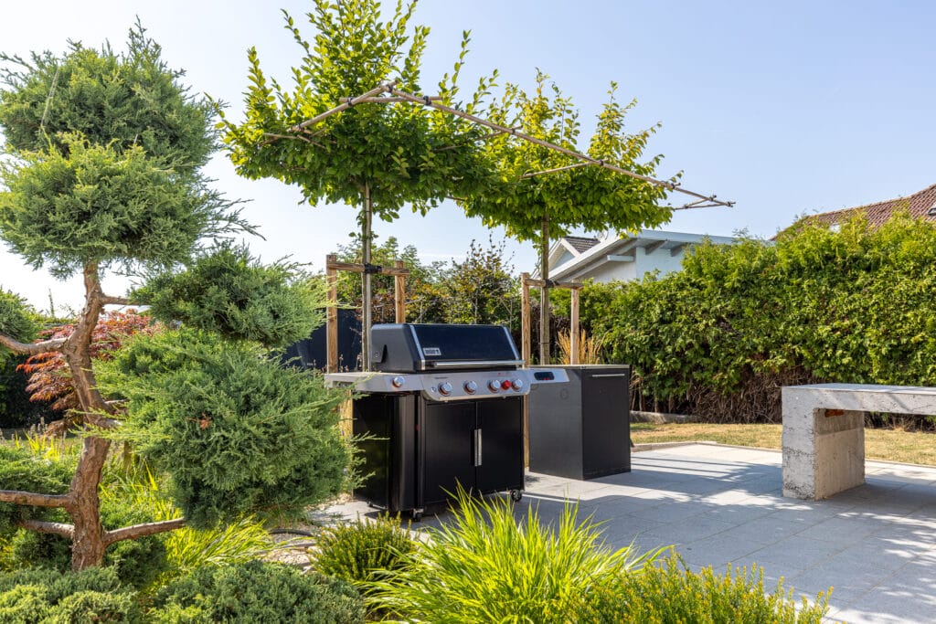 Der Grillplatz im Garten mit Bäumen die als Sonnenschutz dienen