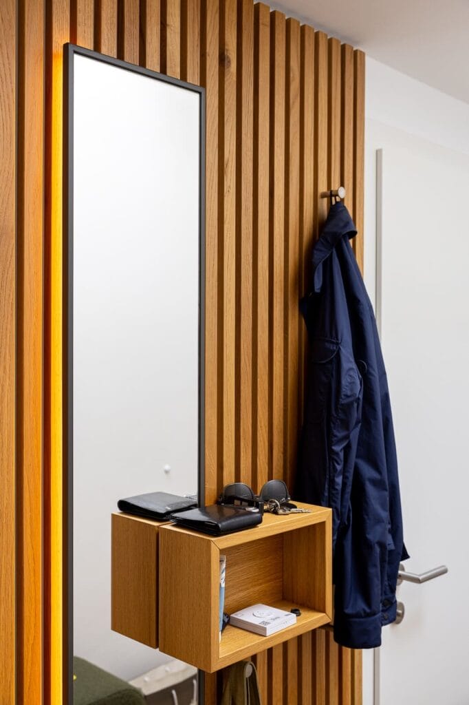 Garderobe mit Holzlamellen-Panel, einem langen Spiegel und einer Ablage